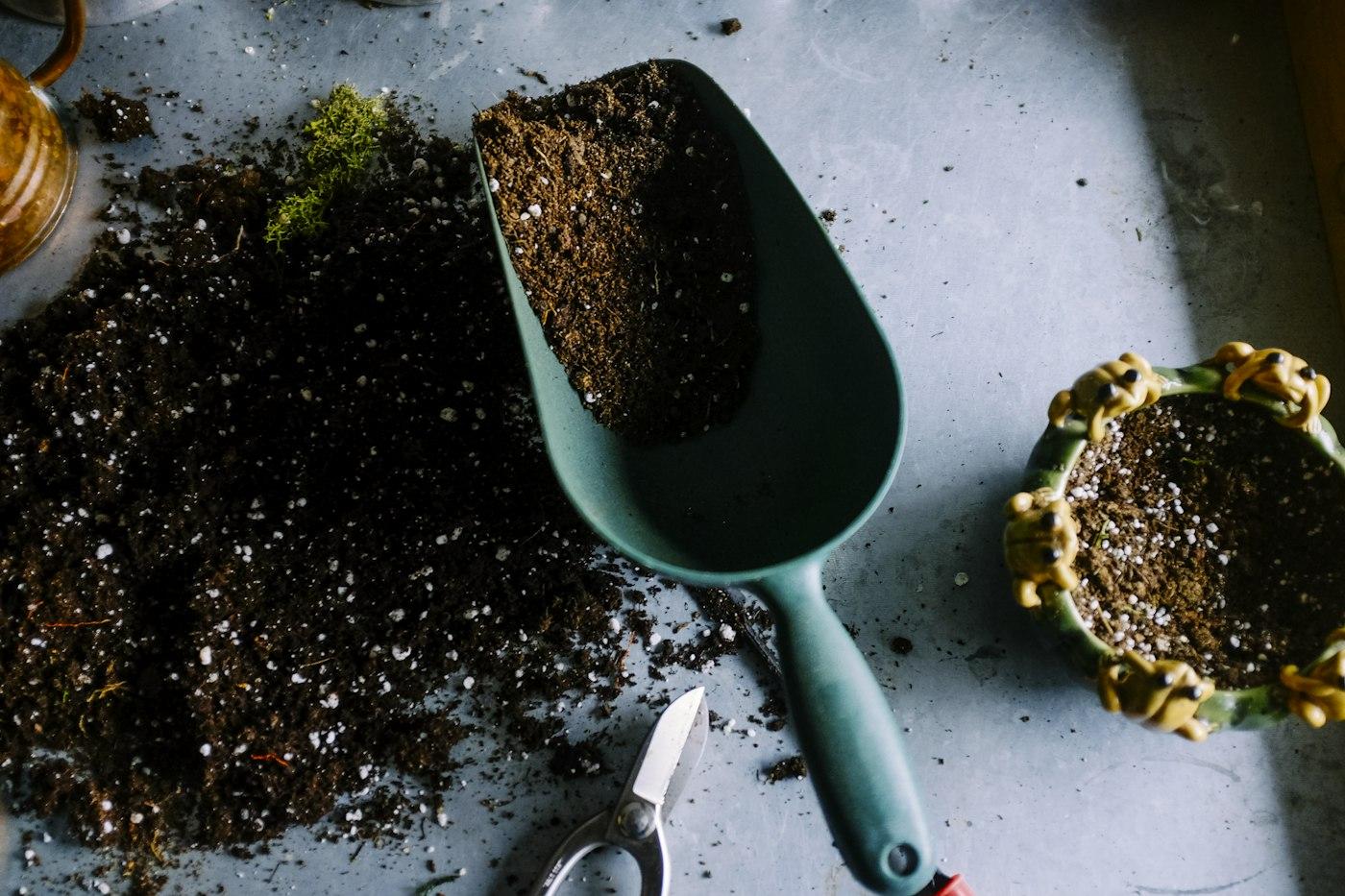 Dark potting soil and a garden trowel on a work table